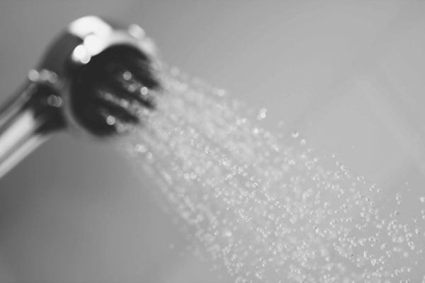shower nozzle spraying water on grey background blog header